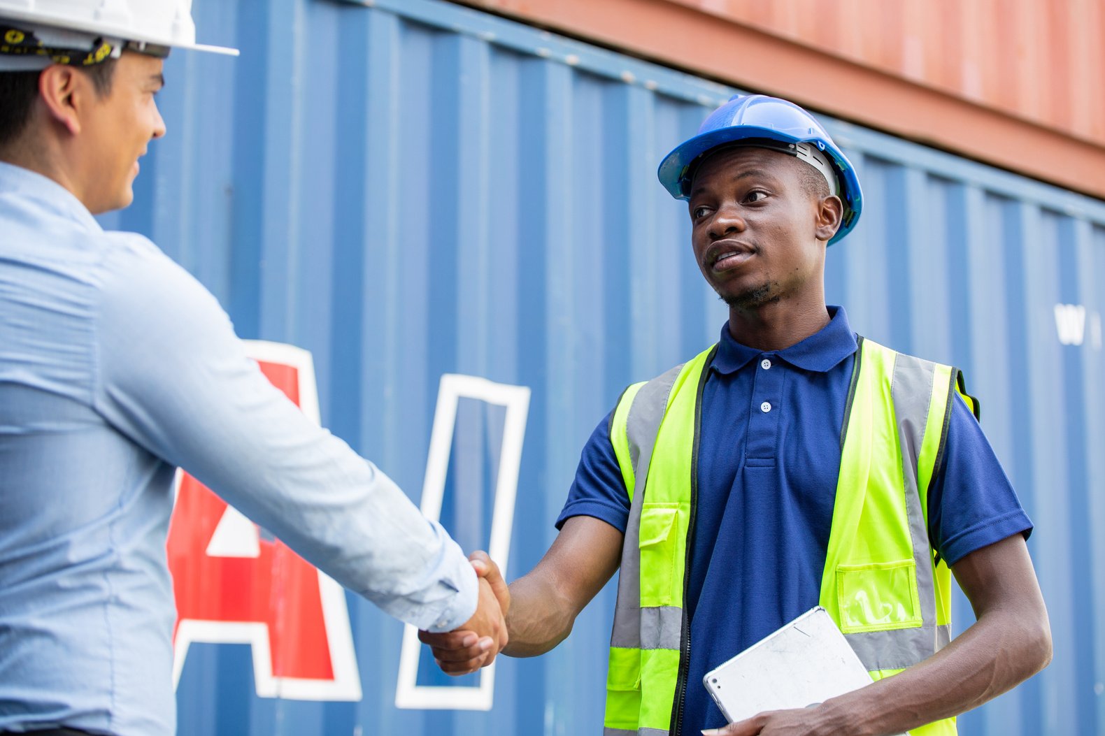 African American construction site worker handshaking with engin